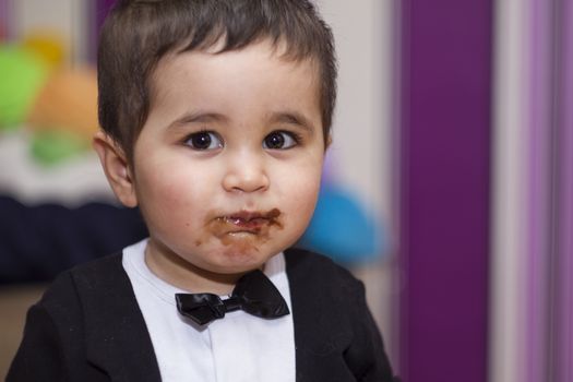 Happy, Adorable happy baby eating chocolate, wearing suit and bow tie