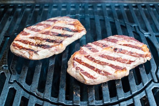 two entrecote beef steaks being grilled on the bbq