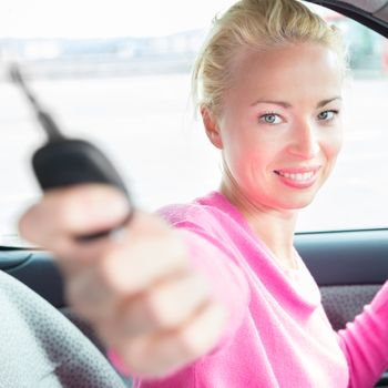 Woman driver showing car keys. Young female driving happy about her new car or drivers license. Caucasian model.