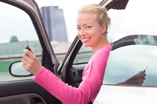 Woman driver showing car keys. Young female driving happy about her new car or drivers license. Caucasian model.