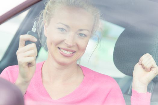 Woman driver showing car keys. Young female driving happy about her new car or drivers license. Caucasian model.