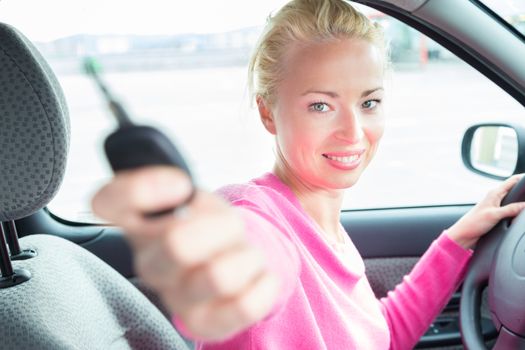 Woman driver showing car keys. Young female driving happy about her new car or drivers license. Caucasian model.