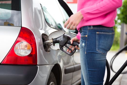 Closeup of woman pumping gasoline fuel in car at gas station. Petrol or gasoline being pumped into a motor vehicle car.