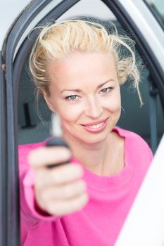 Woman driver showing car keys. Young female driving happy about her new car or drivers license. Caucasian model.