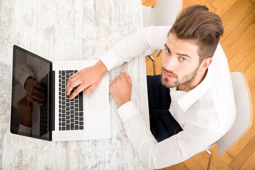 A young man sitting at the table with a laptop computer.