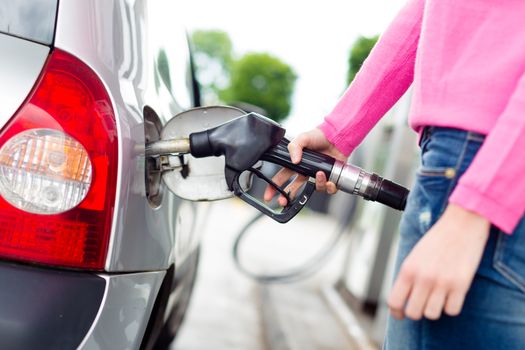 Closeup of woman pumping gasoline fuel in car at gas station. Petrol or gasoline being pumped into a motor vehicle car.