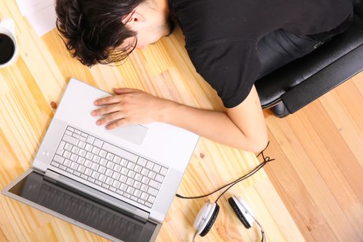 A young hispanic man falling asleep at the office desk.