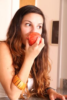 A young adult woman with fruits and wine in the kitchen.