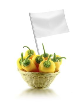 Healthy and organic food concept. Fresh Yellow chili pepper in straw dish with flag showing the benefits or the price of fruits.