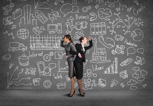 two business women holding hands, looking in different directions, teamwork