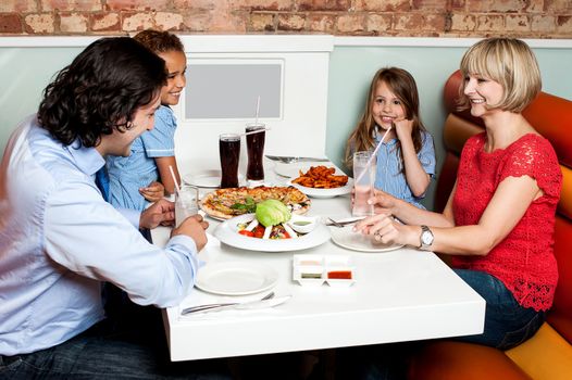Happy couple and their children sitting in restaurant