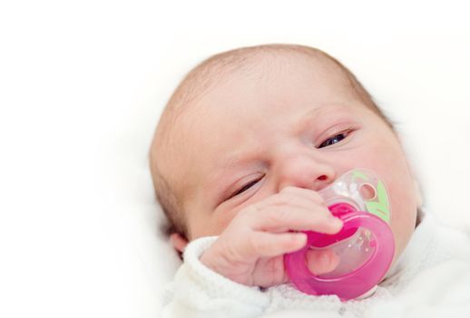 Face of adorable baby with pacifier in mouth looking at camera, the first hours of the new life
