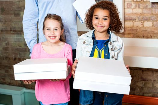 Attractive little girls posing with pizza boxes