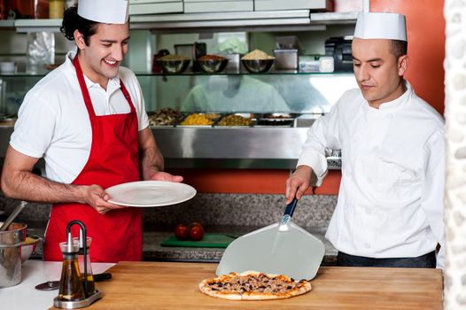 Chef placing freshly baked pizza on the table