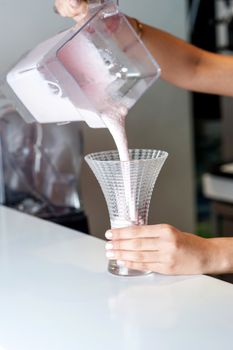 Close-up of woman pouring milkshake into glass