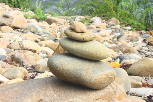 Stones pyramid near small river symbolizing zen, harmony, balance