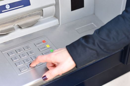 Woman hand entering code into atm machine