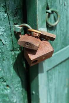 Old rusty padlocks on green door close up 