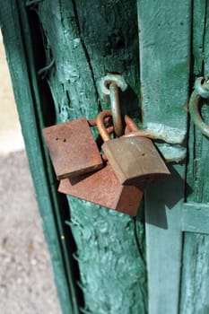 Old rusty padlocks on green door close up 