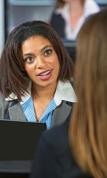 Amazed Black woman talking with friend in restaurant