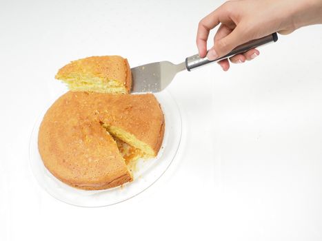 Female person removing a slice from fresh baked cake