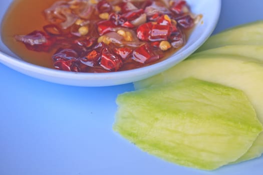 mangoes with sauce, mangoes dipped into a sweet fishy paste with dried shrimp and red onions in plate