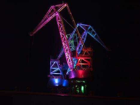 multicolored illumination of shipyard cranes, led lights, night shot