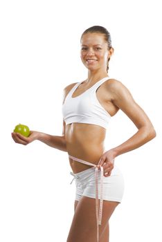 young athletic girl measuring waist measuring tape and holding a green apple, concept of healthy eating, isolated on white background