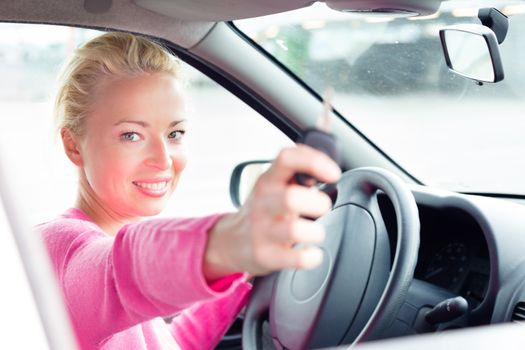 Woman driver showing car keys. Young female driving happy about her new car or drivers license. Caucasian model.