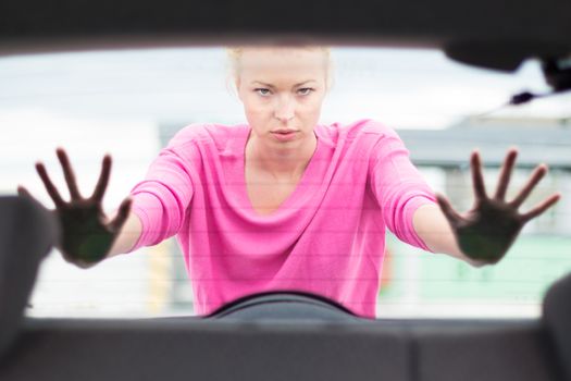 Self-sufficient, strong, young woman pushing a car. Engine breakdown.