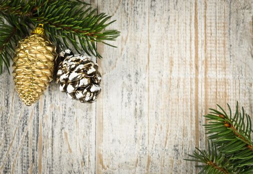 Christmas golden balls and pine cone on spruce branch with wooden background