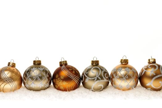 Row of golden Christmas balls with festive designs on snow