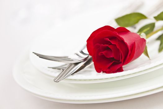 Romantic restaurant table setting with red rose on plates