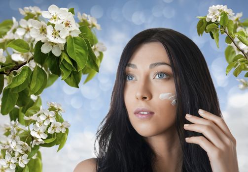 woman causes cream on the background of Apple blossoms