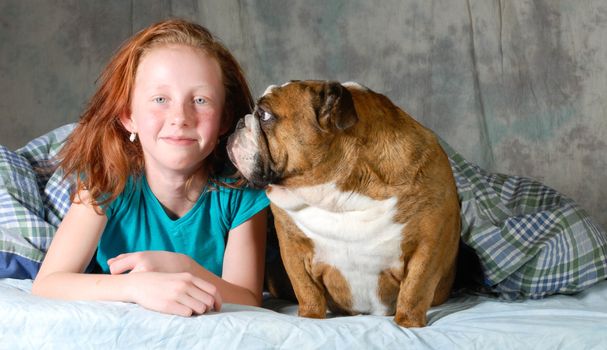 girl with her pet bulldog in bed