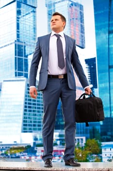 successful businessman with a briefcase on the background skyscrapers of business center