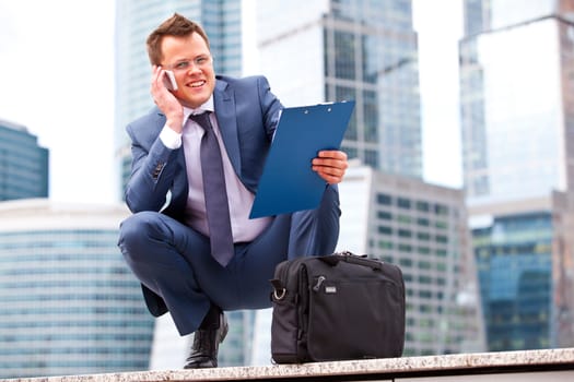 successful businessman talking on the phone on the background of office buildings