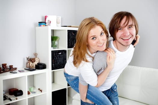 young man carrying girlfriend on his back in home