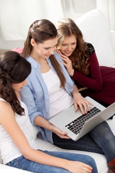 three young  women resting with notebook on floor near sofa, at campus