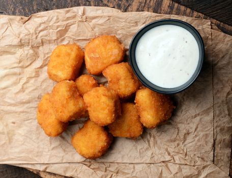 Chicken nuggets with garlic sauce on old wooden background