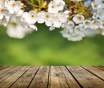 Empty wooden deck table with spring flowers in background