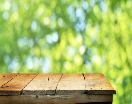 Empty wooden deck table with fresh green background