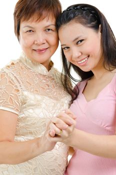 Mixed race beautiful Asian family portrait. Elderly mother and adult daughter holding hands bonding isolated on white background.