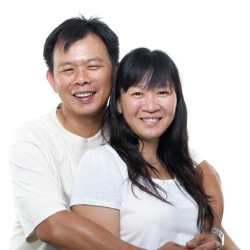 Happy southeast Asian mature couple hugging and smiling, isolated on white background.