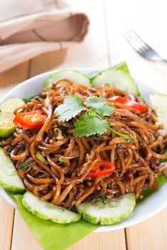 Asian style spicy fried noodles, ready to serve on dining table.