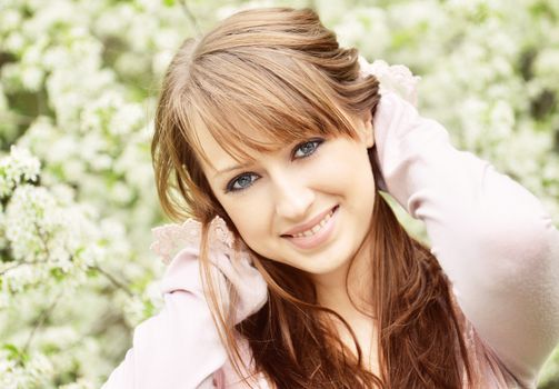 Beautiful girl posing over spring flowers background