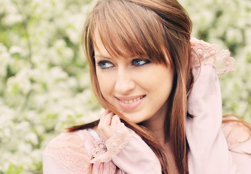 Beautiful girl posing over spring flowers background