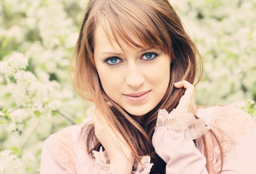 Beautiful girl posing over spring flowers background