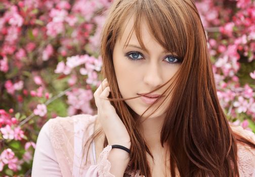 Beautiful girl posing over spring flowers background