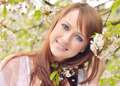 Beautiful girl posing over spring flowers background